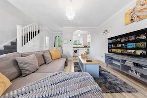 Ein modernes Wohnzimmer mit Sofa, Couchtisch, Fernseher und einer Treppe.