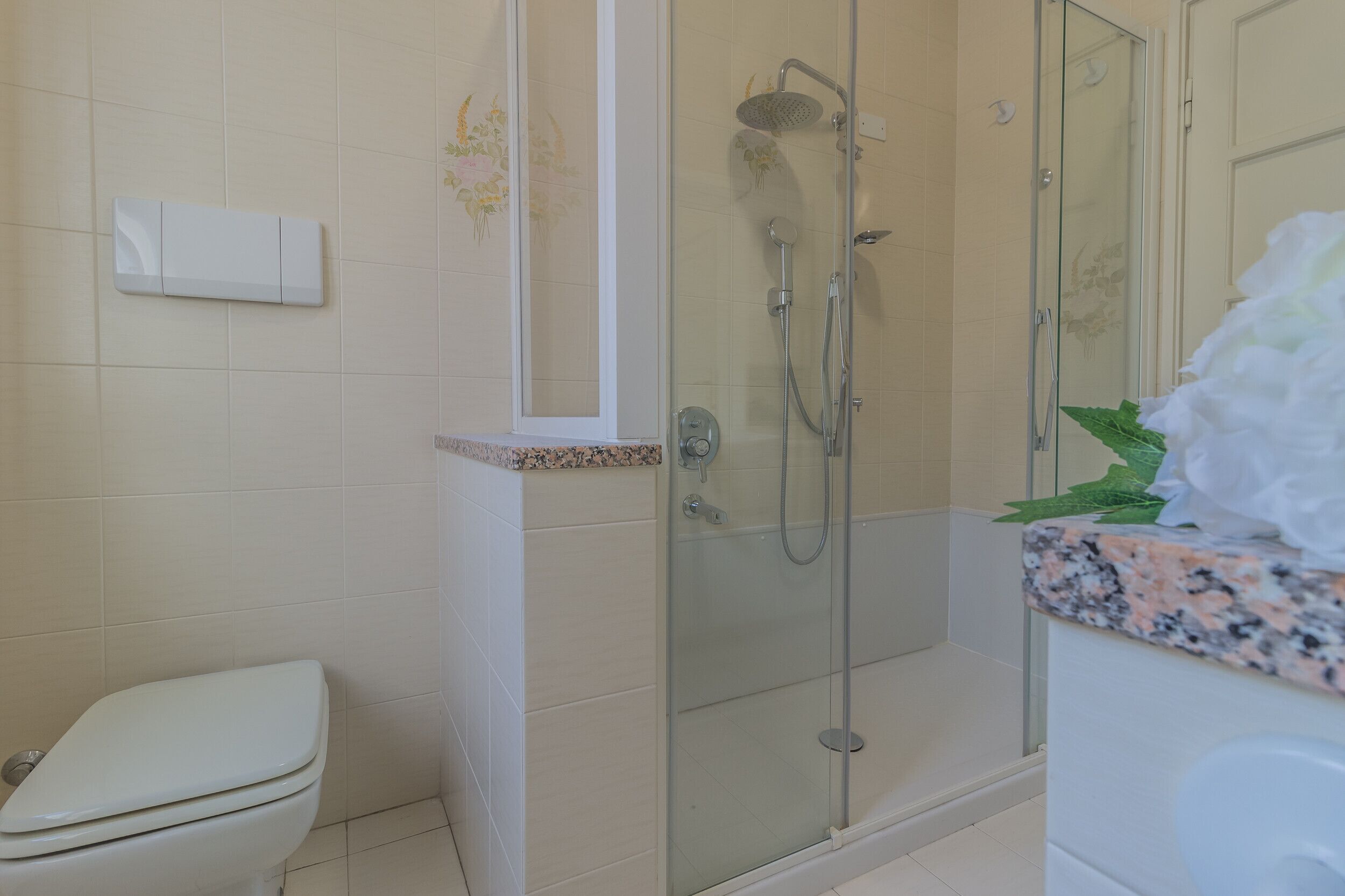 A bathroom with a toilet, a glass-enclosed shower, and a granite countertop.