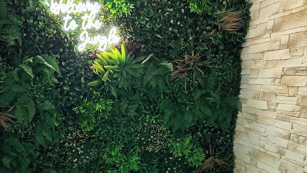 Ein Wellnessbereich mit Whirlpool, einer Neonreklame und einer mit Grünpflanzen bewachsenen Wand.
