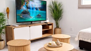 Ein modernes Wohnzimmer mit Flachbildfernseher, Holzmöbeln und Blick auf einen Wasserfall.