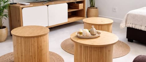 A modern living room with a flat-screen TV, wooden furniture, and a view of a waterfall.