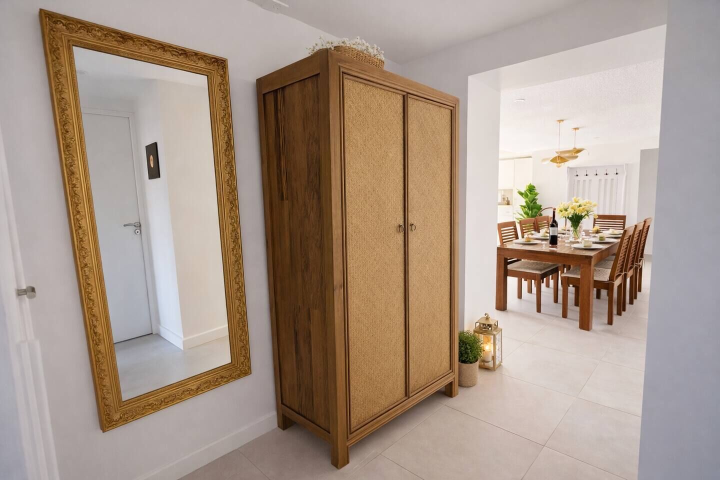 A room with a large mirror, a wooden cabinet, and a dining area with a table and chairs.