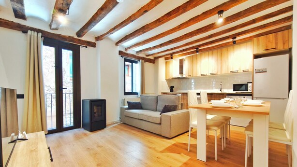 Um interior moderno com soalho de madeira, um sofá, uma mesa de jantar e uma zona de cozinha.