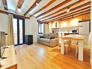 A modern interior with a wooden floor, a sofa, a dining table, and a kitchen area. - House in La Vila medieval de La Pobla de Lillet (La Pobla de Lillet)