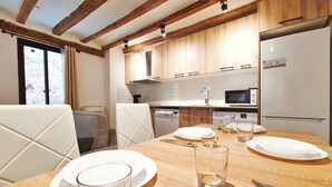 Uma sala de jantar com uma mesa de madeira posta para quatro pessoas, completa com pratos, copos, talheres e um micro-ondas.