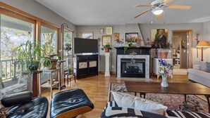 Een ruime woonkamer met een open haard, een televisie en een plafondventilator.