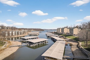A riverside marina with docked boats, a covered walkway, and buildings along the riverbank. - Bristol Bay 34 - 3 Bdrm waterfront condo (Lake Ozark)