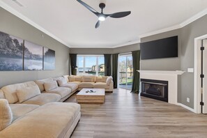 A living room with a sectional sofa, a coffee table, a fireplace, and a television mounted on the wall. - Bristol Bay 34 - 3 Bdrm waterfront condo (Lake Ozark)