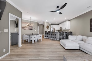 A modern kitchen with white cabinets, a dining area with a round table and chairs, and a living room with a sectional sofa. - Bristol Bay 34 - 3 Bdrm waterfront condo (Lake Ozark)