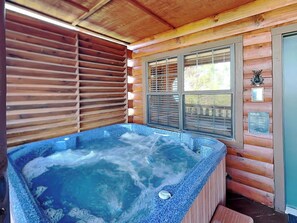 Une cabane en bois avec un jacuzzi, des stores en bois et une fenêtre agrémentée d’un objet décoratif.