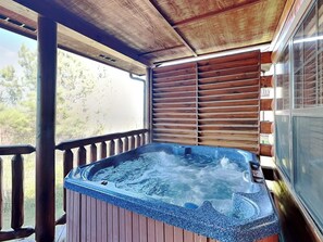Un bain à remous sur une terrasse en bois, avec vue sur les arbres.