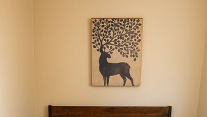 A bed with a wooden frame, dark gray and orange bedding, and a wall-mounted artwork of a deer. - Cabana (Miami)