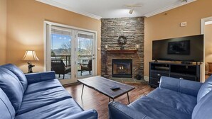 Ein Wohnzimmer mit Kamin aus Stein, einem Fernseher und blauen Ledersofas.