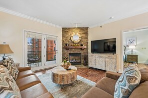 A living room with a fireplace, television, and comfortable seating. - 🌄Baskins Creek 210 | Walk to Downtown | Cozy Gatlinburg Condo🏔️ (Gatlinburg)