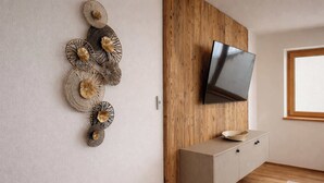 A modern room with a wooden wall panel, a mounted TV, a wooden cabinet, and decorative wall art.