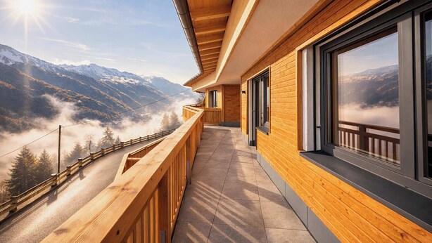 A wooden balcony with a view of mountains and a road.