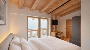 Quarto com cama, escrivaninha, televisão e varanda.
