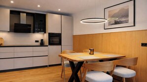 Eine moderne Küche mit Holzschränken, einem Einbauofen und einem Essbereich mit Holztisch und -stühlen.