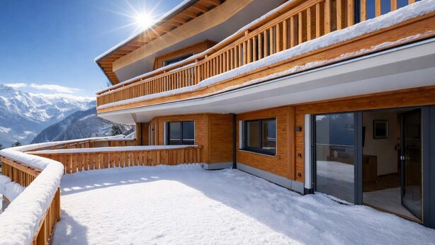 Ein mehrstöckiges Holzgebäude mit Balkon, verschneitem Gelände und einem Bergpanorama im Hintergrund.