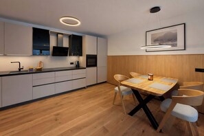 Eine moderne Küche mit weißen Schränken, einem Holztisch und einem gerahmten Bild an der Wand.