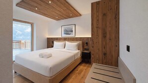 A bedroom with a large bed, wooden ceiling, a nightstand, a bedside table, and a framed picture on the wall.