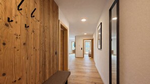 A hallway with wooden paneling, a bench, and framed pictures on the walls.