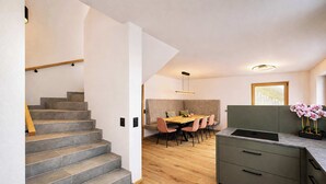 A modern kitchen with grey cabinets, a wooden dining table, and a staircase with grey steps.