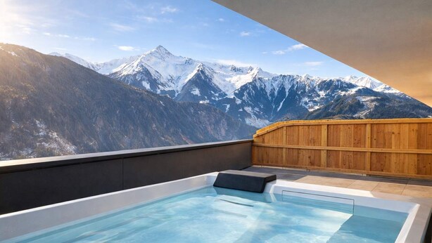 A hot tub with a mountain view, wooden deck, and a clear sky.