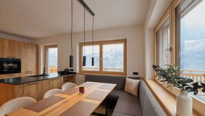 Eine moderne Küche mit Holztisch, Sitzgelegenheit, großen Fenstern mit Aussicht und Pendelleuchten.