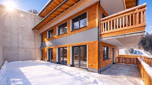 Ein modernes, zweistöckiges Gebäude mit Holzfassade, großen Schiebeglastüren und einem Balkon.