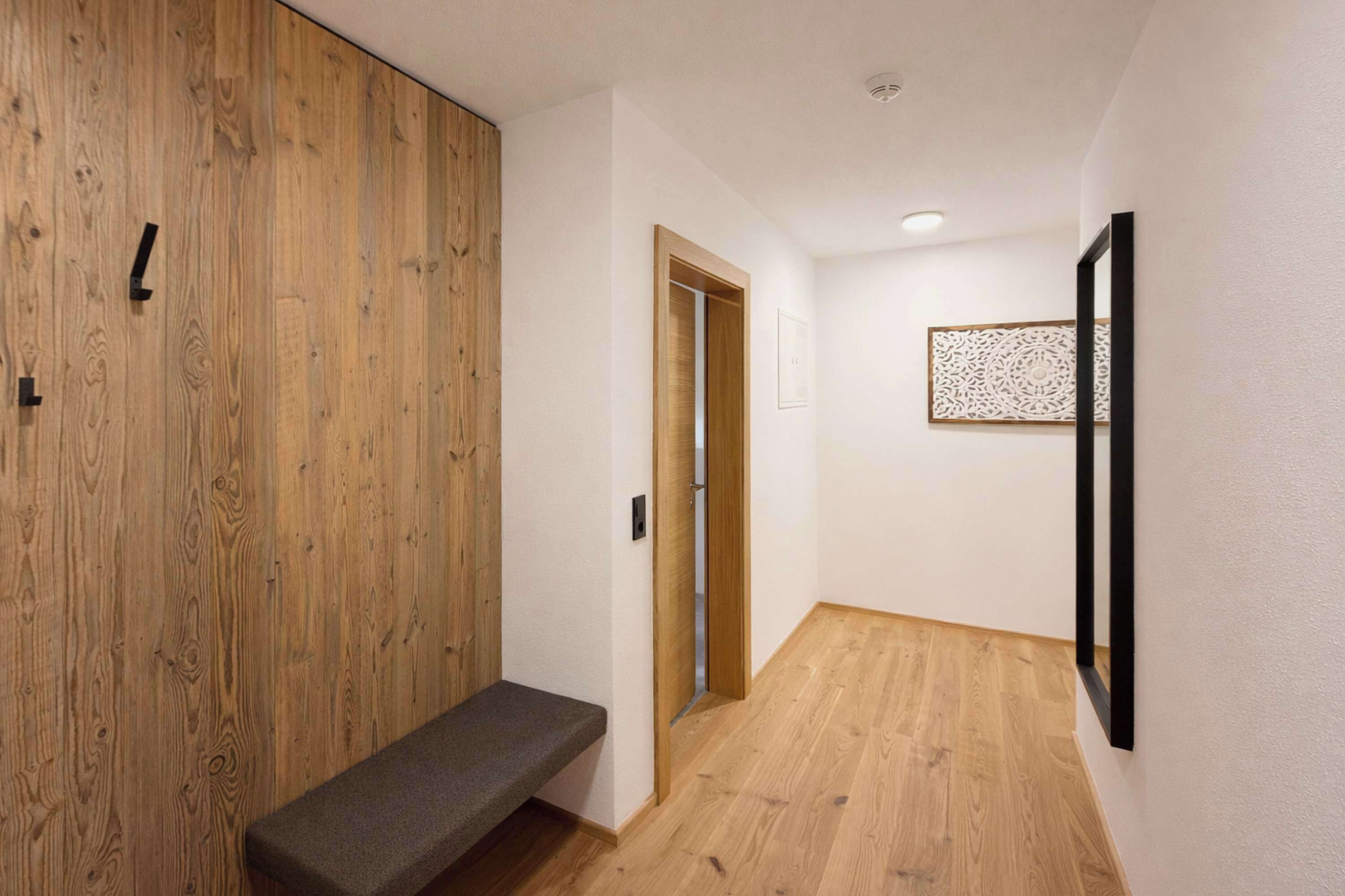 Ein Korridor mit Holzwandverkleidung, einer Sitzbank, einer Tür und einem Wandbild.