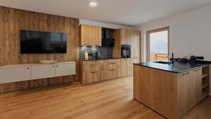 Eine moderne Küche mit Holzausstattung, einem integrierten Fernseher und einem großen Fenster.