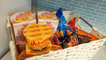 A basket containing food items including Velveeta cheese, Nissin Cup Noodles, and other snacks.