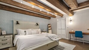 Un dormitorio con cama, mesitas de noche, escritorio, silla y armario.