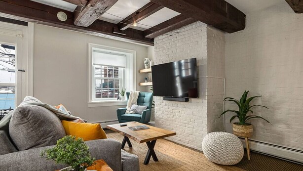 Sala de estar con sofá, sillón, mesa de centro, televisor y plantas en macetas.