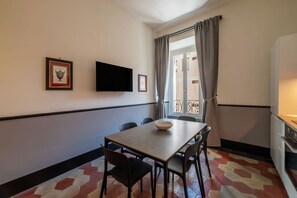 A dining area with a table, chairs, a flat-screen TV, and a window with curtains. - Toscana 4 - FromHometoRome (Roma)