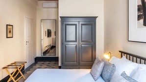A bedroom with a bed, a wardrobe, a mirror, and a door leading to a bathroom. - Toscana 4 - FromHometoRome (Roma)
