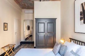 A bedroom with a bed, a wardrobe, a mirror, and a door leading to a bathroom. - Toscana 4 - FromHometoRome (Roma)