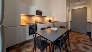 A modern kitchen with white cabinets, a marble backsplash, and a dining area with a table and chairs. - Toscana 4 - FromHometoRome (Roma)