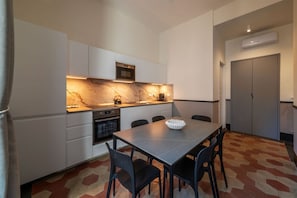 A modern kitchen with white cabinets, a marble backsplash, and a dining area with a table and chairs. - Toscana 4 - FromHometoRome (Roma)