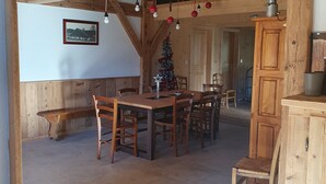 Un coin repas rustique en bois, avec une table et des chaises, un banc, un sapin de Noël et un buffet.