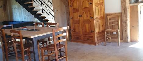 A wooden dining area with a table and chairs, a staircase, and a large wooden cabinet.