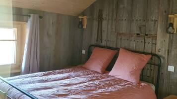 Un lit simple avec un cadre en métal, un plafond en bois et un mur en bois.
