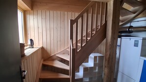 Un escalier en bois avec une rampe en métal, un meuble blanc et une fenêtre donnant sur un beau paysage.