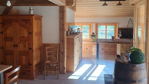 Une cuisine rustique avec des meubles en bois, un coin repas avec une chaise et un grand tonneau.