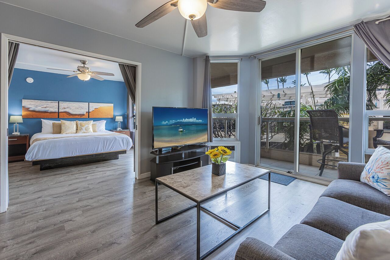 A modern hotel room with a bed, TV, balcony, and a coffee table.