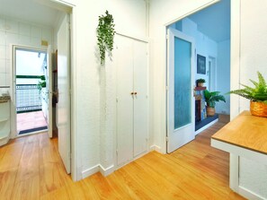 A hallway with a white textured wall, wooden flooring, and a door with a frosted glass panel. There are potted plants on the right side. - Apartment in Vilassar de Mar, Barcelona Coast (Vilassar de Mar)
