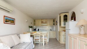Un espacio habitable compacto con kitchenette, comedor y sofá.