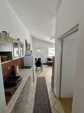 Een keuken met een eethoek, een bank en een deur naar een andere kamer.
