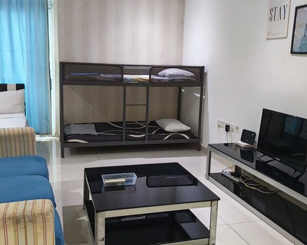 A bunk bed with a TV and a small table in a room with a window and curtains. - KSL Studio Room #115 (Johor Bahru)